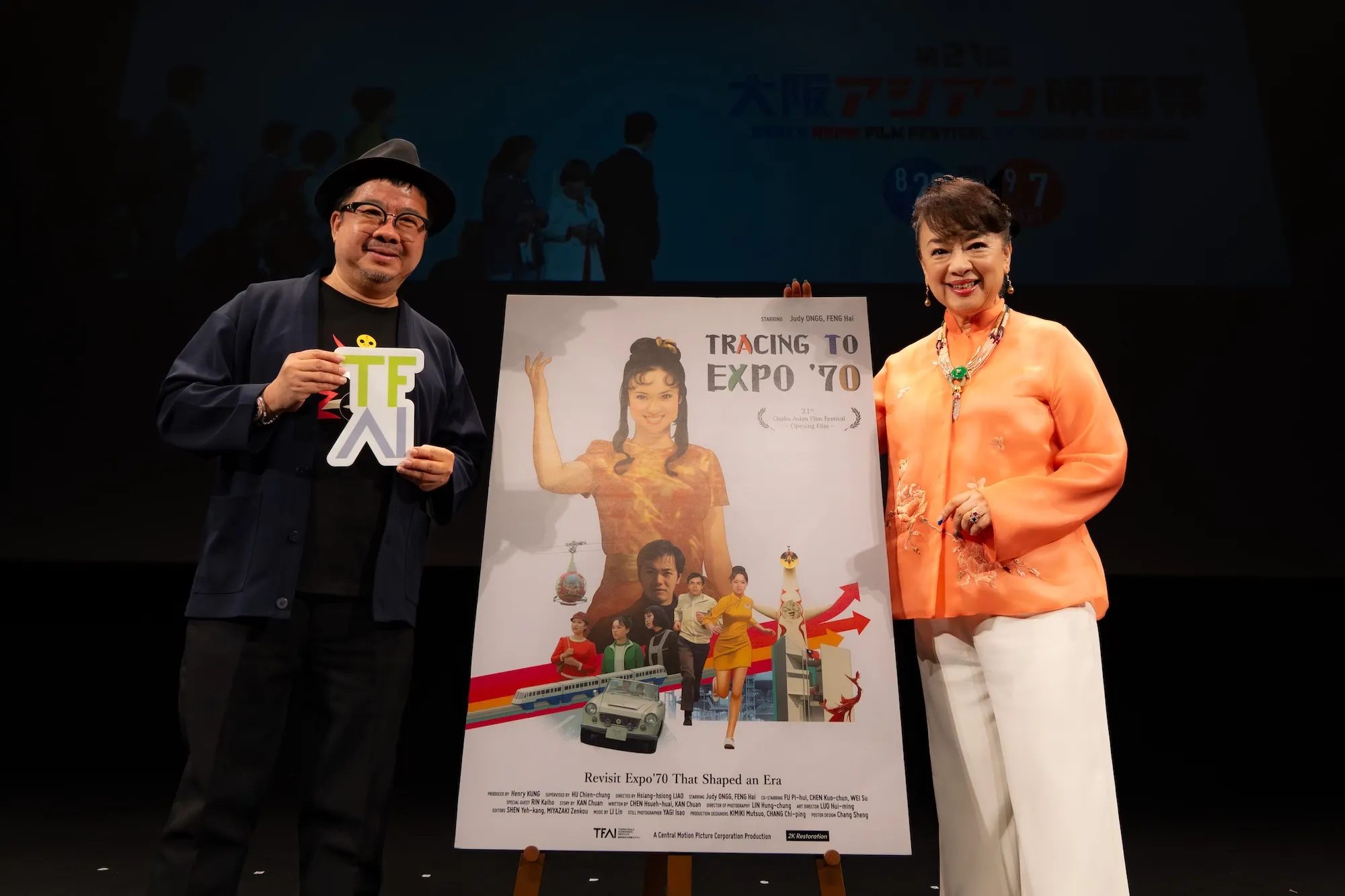 対談後、『万博追跡』の映画ポスター前で記念撮影に臨むジュディ・オング氏（右）と国家電影及視聴文化センターの褚明仁董事長（左）。（写真提供＝大阪アジアン映画祭）