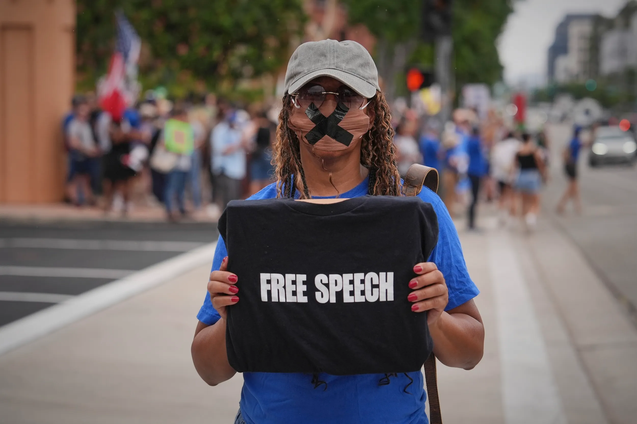 2025年9月18日，美國加州柏本克，迪士尼總部外，梅洛迪・庫柏（Melody Cooper）手持「言論自由」（Free Speech）標語，參加聲援吉米・金摩（Jimmy Kimmel）的示威活動，回應其深夜節目遭到停播的爭議。（美聯社）