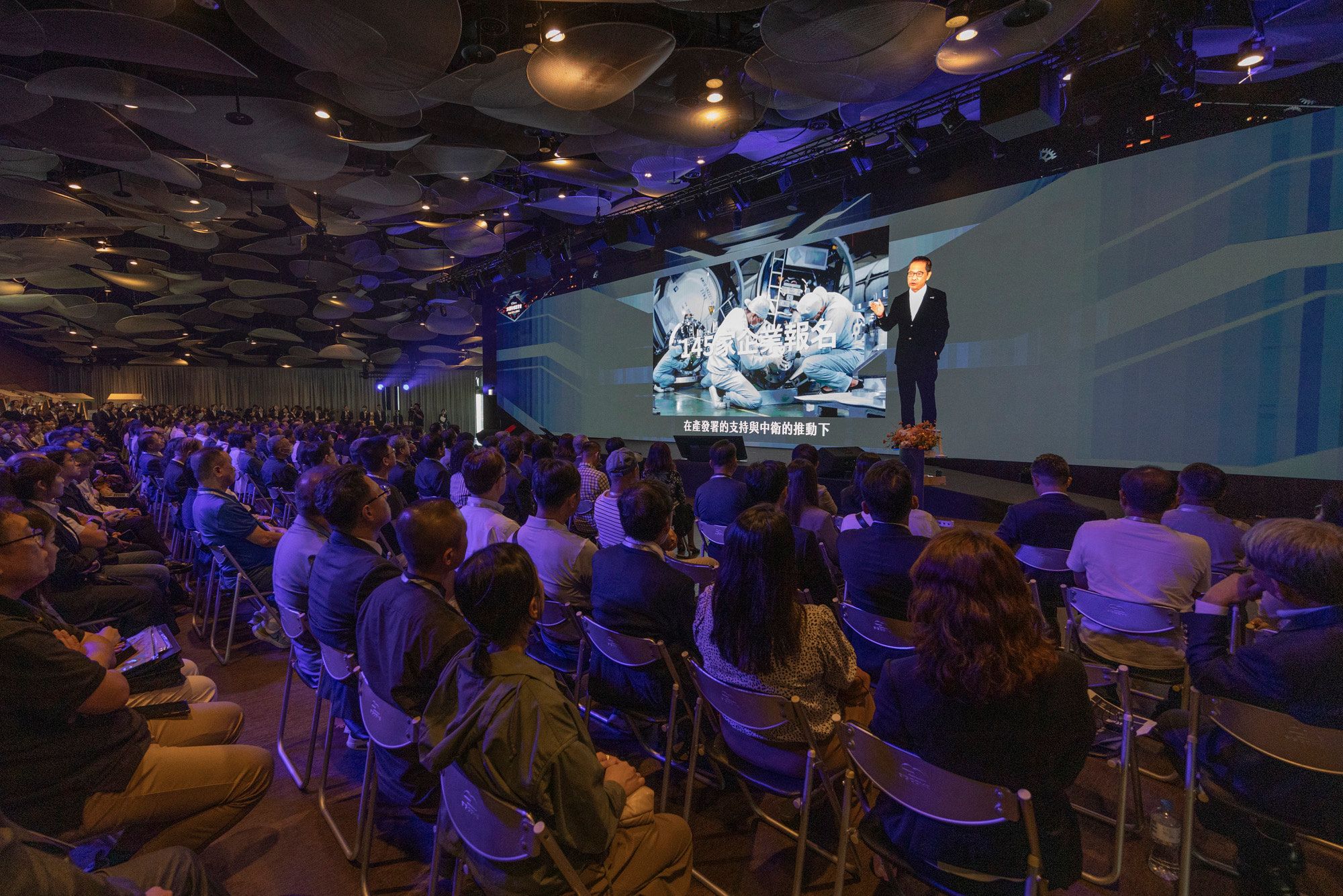 中衛中心運用AI虛擬人像技術，生成董事長謝明達的「AI分身」與本尊同台互動。（圖/中衛中心提供）