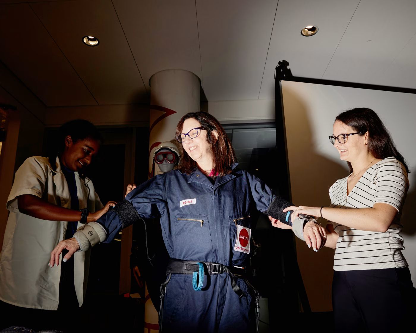 麻省理工學院老年實驗室的研究人員索菲婭・阿什比爾（Sophia Ashebir, 左）和泰勒・布倫南（Taylor Brennan）為本文作者Amy Dockser Marcus穿上年齡模擬服。（華爾街日報）