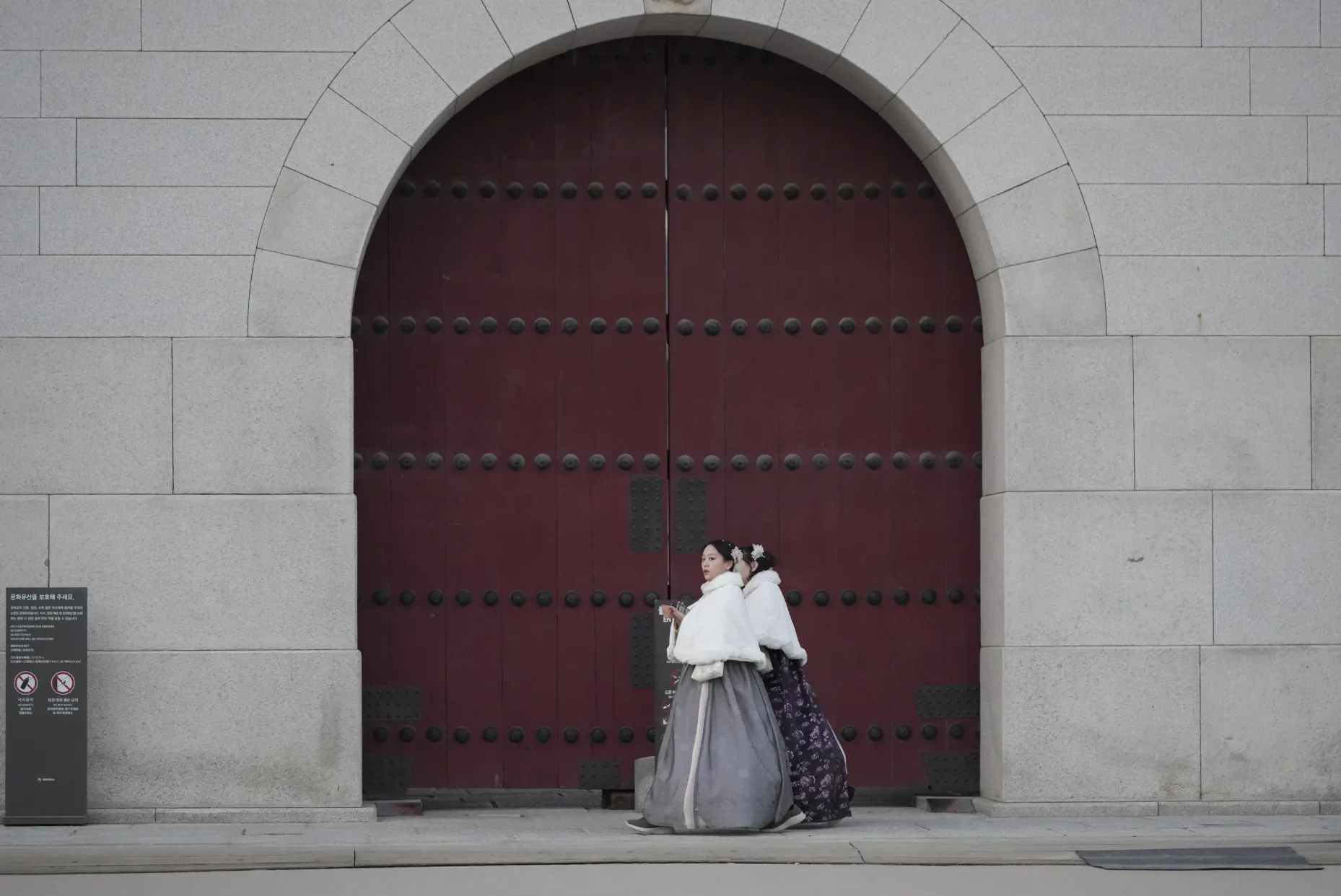 身著韓國穿統服飾（韓服）的遊客在首爾觀光景點光化門前散步。（美聯社）