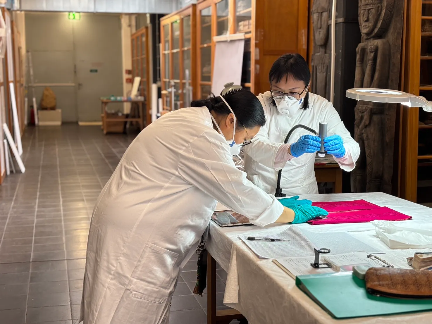 考察團隊成員近距離觀察採集自烏來的桃紅色無袖上衣。(圖/新北市政府原民局提供)。