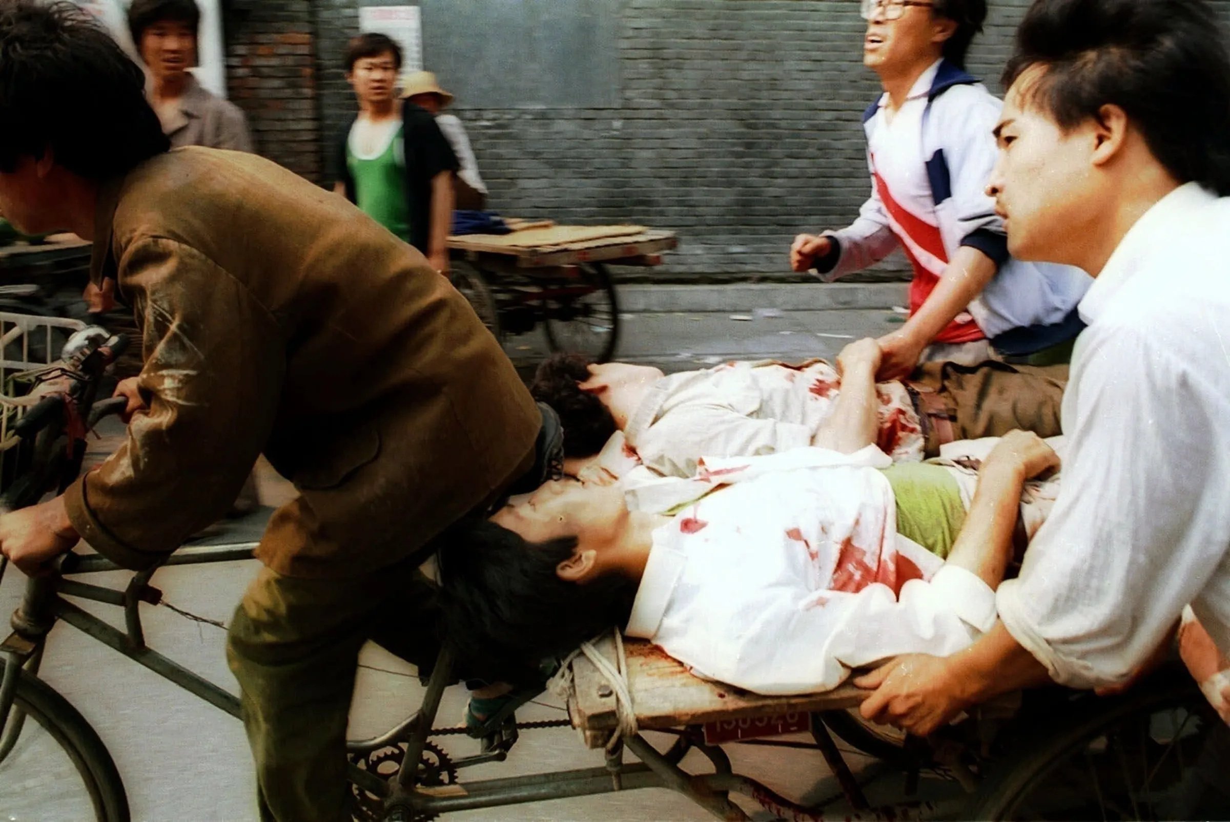 1989年6月4日，中國北京，解放軍朝天安門廣場外聚集的人群開槍後，一名黃包車伕在路人協助下將傷者送往附近醫院。（美聯社）