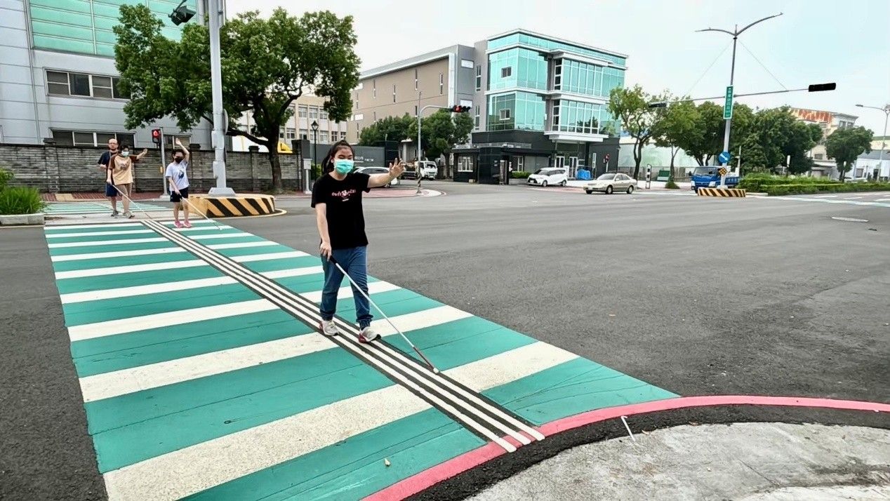 視覺功能障礙引導行穿線由三條白色實線貫穿斑馬線，視障生所使用的白手杖可以感應軌道方向，助其正確、安全地穿越馬路。(圖/台中市政府新聞局)