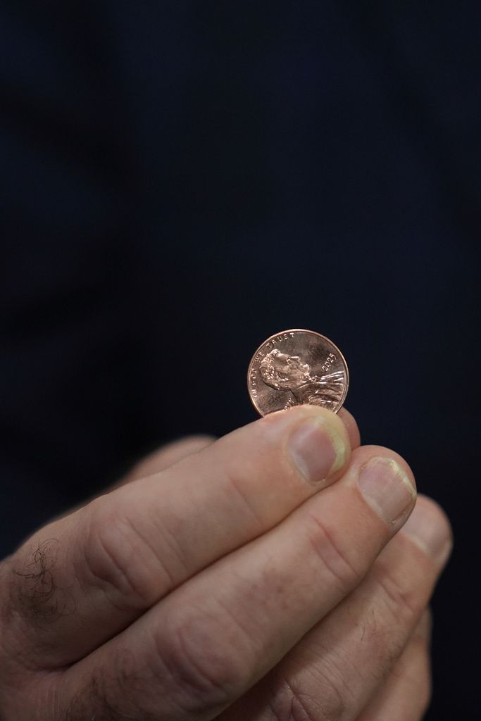 2025年11月12日。在美國費城鑄幣局，財政部司庫畢治（Brandon Beach）手握最後一批的1美分硬幣。（AP）