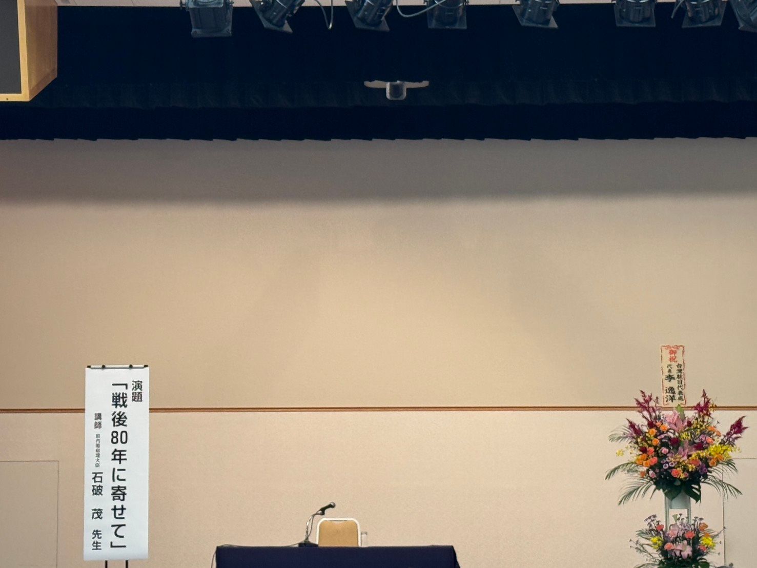 20251203-日本台湾親善協会主催の「時局演講会」に元首相の石破茂氏を招待し、「戦後80周年」をテーマに講演が行われた。駐日代表処代表李逸洋氏が花籠を贈る。（黄信維撮影）