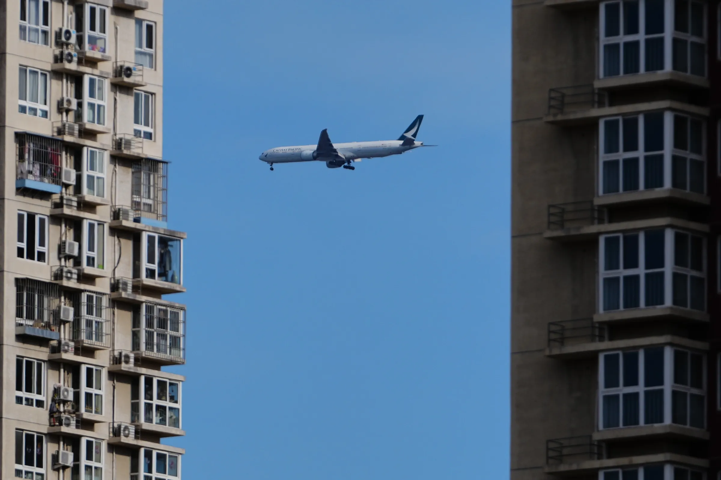 2025年12月1日，中國北京，國泰航空一架客機準備降落首都國際機場時，飛過住宅大樓上空。（美聯社）