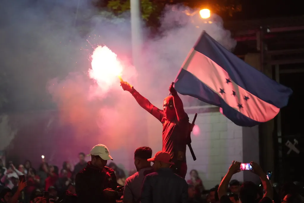 宏都拉斯總統大選陷入開票膠著，支持執政黨的群眾揮舞國旗走上街頭。（美聯社）