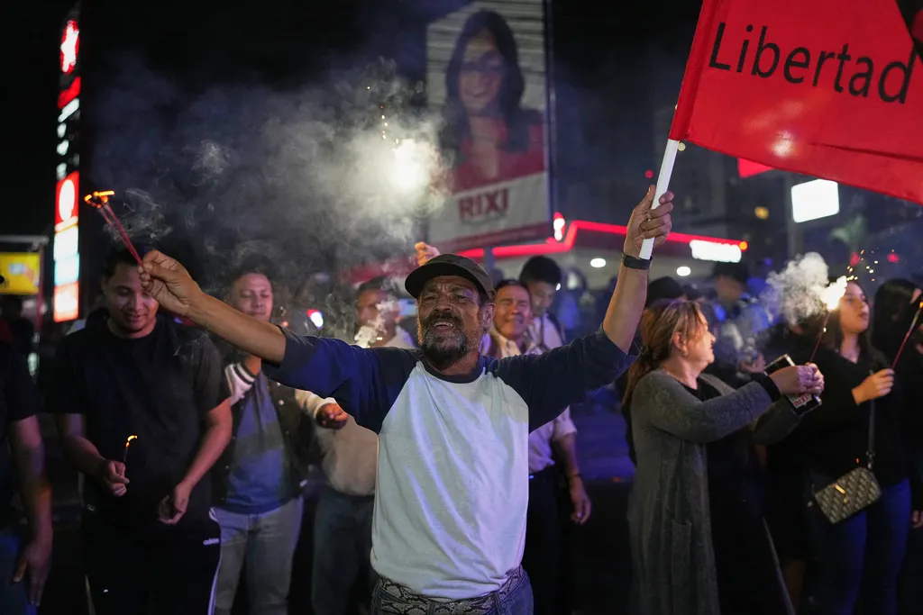 宏都拉斯總統大選陷入開票膠著，支持執政黨的群眾揮舞旗幟走上街頭。（美聯社）