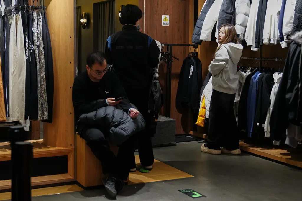 中國北京民眾路過一處服飾門市進行試穿選購。（美聯社）