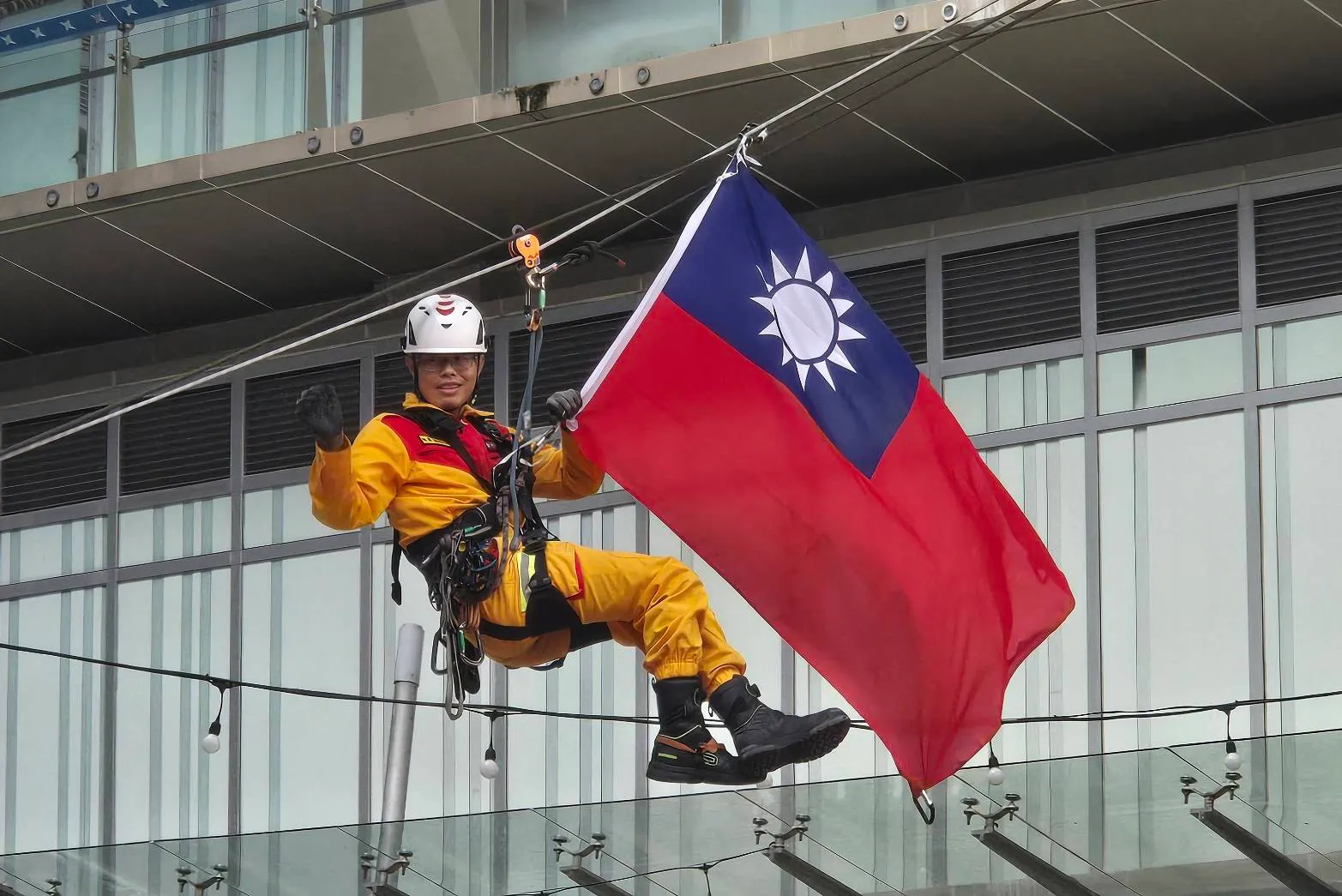 新竹市消防局特搜隊員手持國旗演練斜降救援項目。（圖／方詠騰攝）