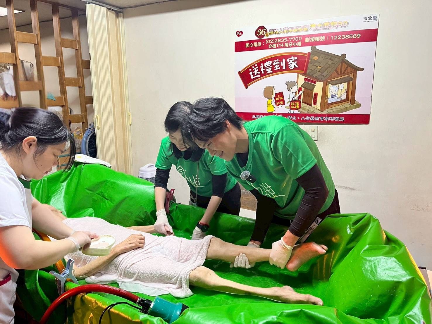 創世基金會舉辦「第36屆寒士吃飽30—送禮到家」說明會，藝人黃鐙輝擔任創世到宅義工，為王爺爺原床泡澡。（創世基金會提供）