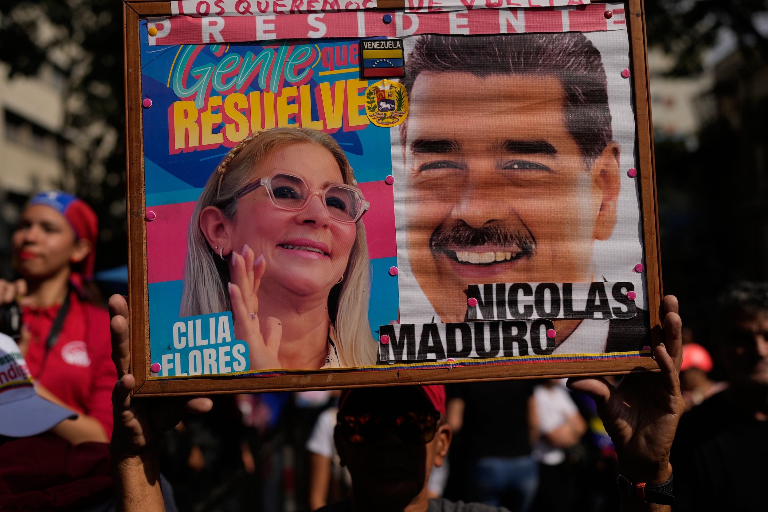 2026年1月6日，委內瑞拉加拉加斯，一名政府支持者在女性遊行中手持委內瑞拉總統尼古拉斯．馬杜洛（Nicolas Maduro）與第一夫人西莉亞．弗洛雷斯（Cilia Flores）的照片，要求兩人回歸。這場遊行距離美軍逮捕馬杜洛夫婦已過三天。（美聯社）