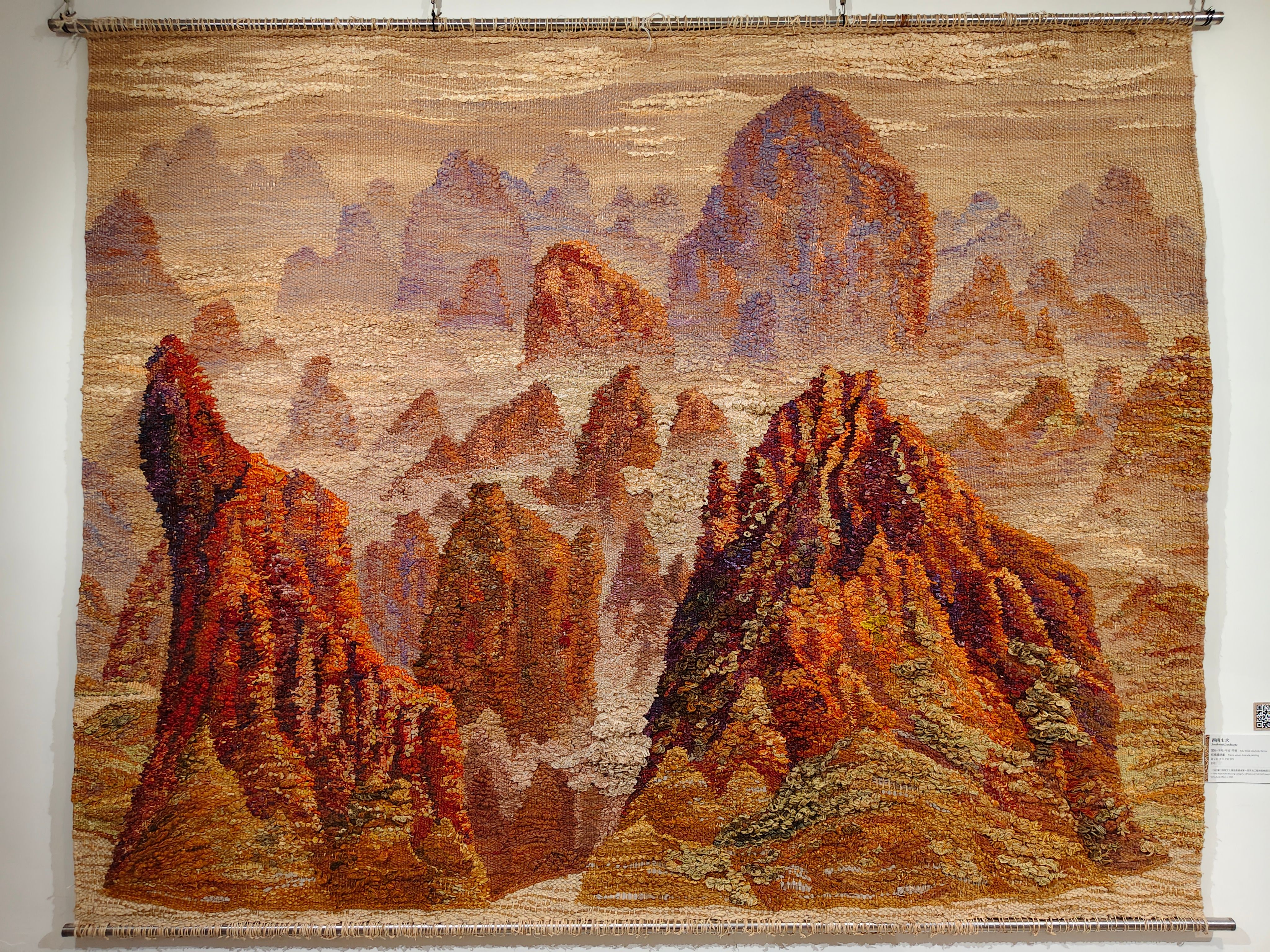 陳景林早期的編織作品「西南山水」是純手工的織錦畫，顏色柔和層次豐富，融合了西方織錦畫、東方緙絲和手工地毯等多種技法，耗時三年才完成，獲得文建會首屆民族工藝獎編織類三等獎。（圖／作者攝）