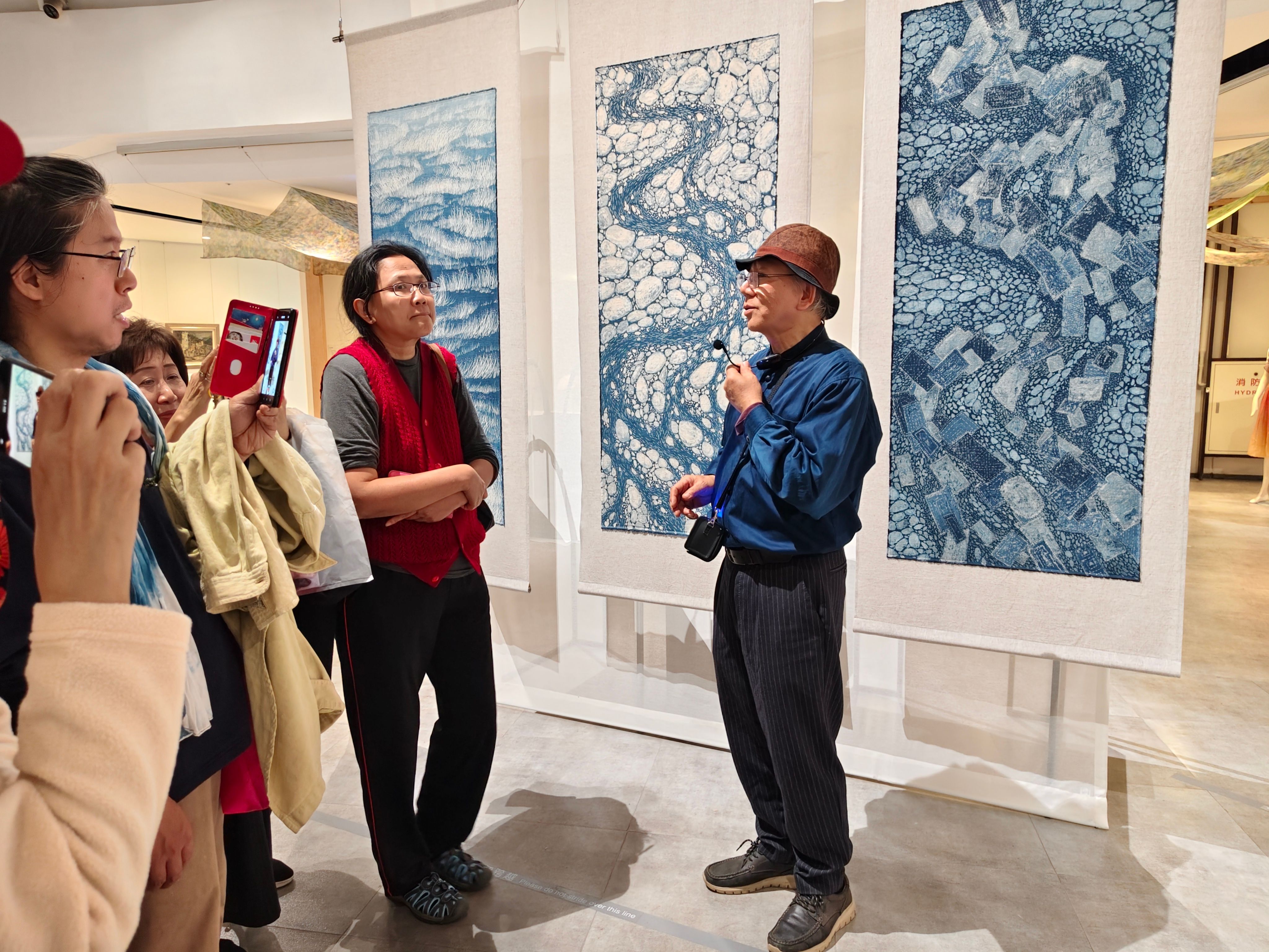 在展場中陳景林向觀者解說作品「土石流三部曲」，希望喚起人們的環保意識。（圖／作者攝）