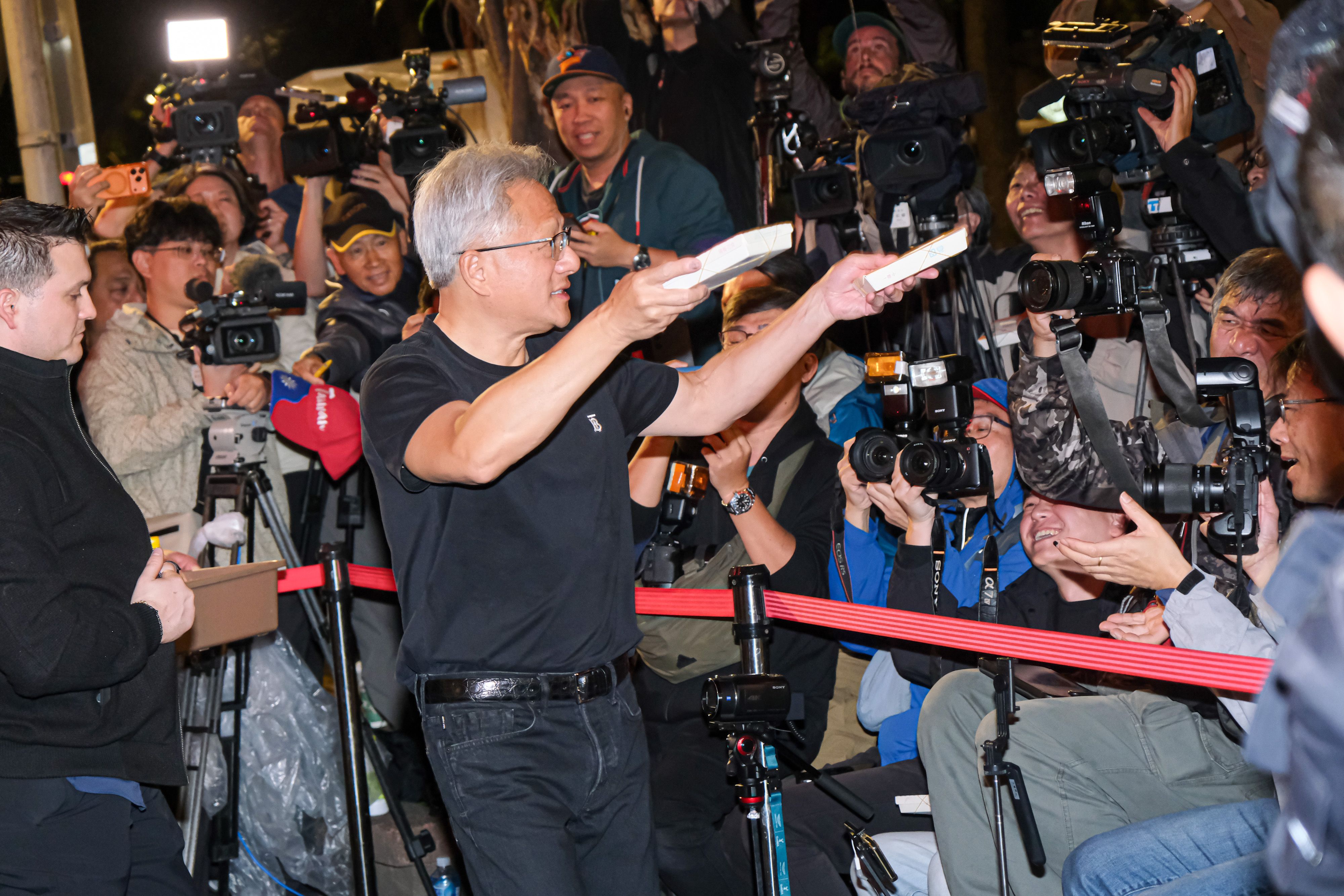 20260131-輝達創辦人暨董事長黃仁勳31日赴磚窯古早味懷舊餐廳出席「兆元宴」，並將油飯分發給現場的媒體記者。（劉偉宏攝）