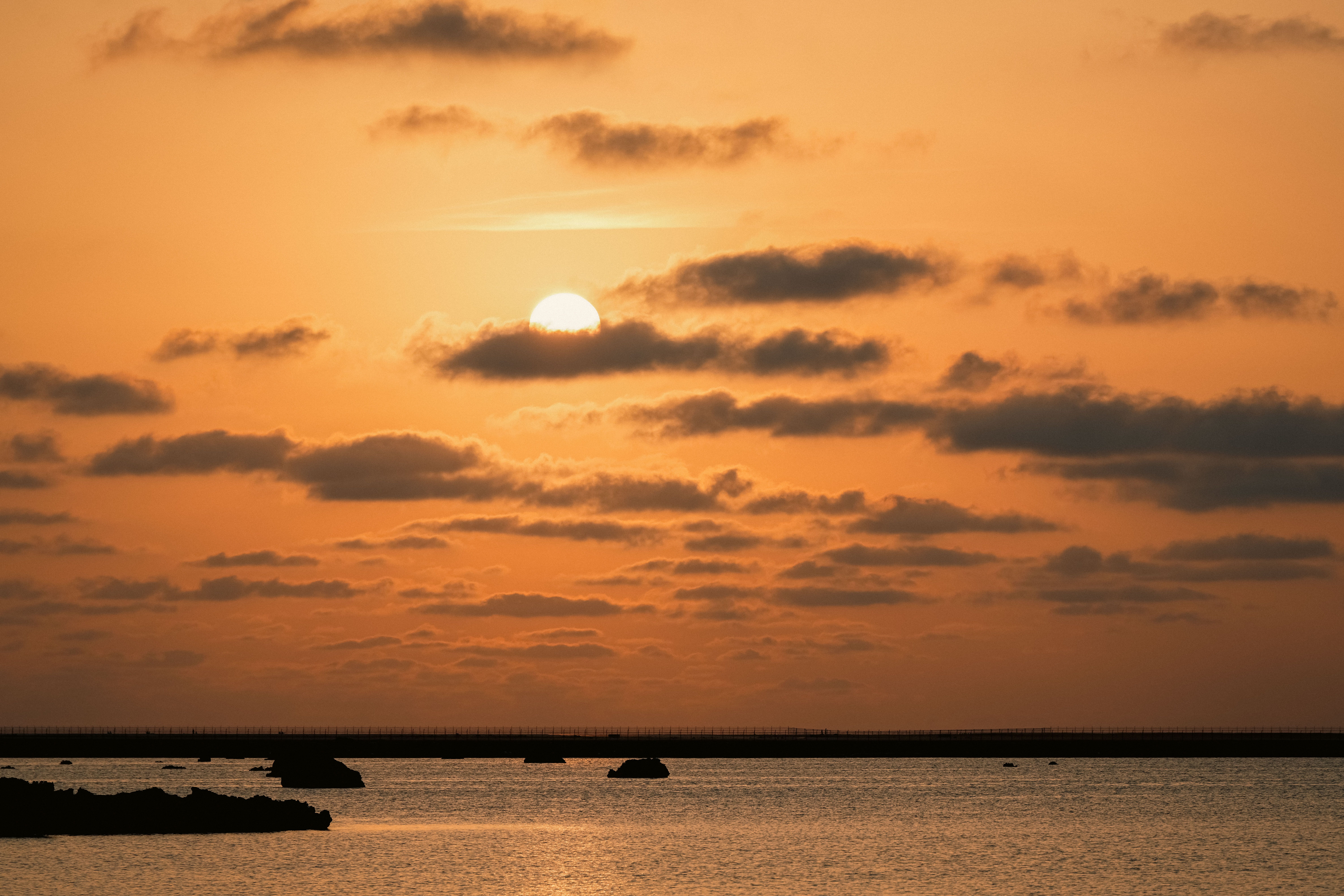 夕陽落入宮古島佐和田之濱的海面，橘金色光暈映照海岸線之美。