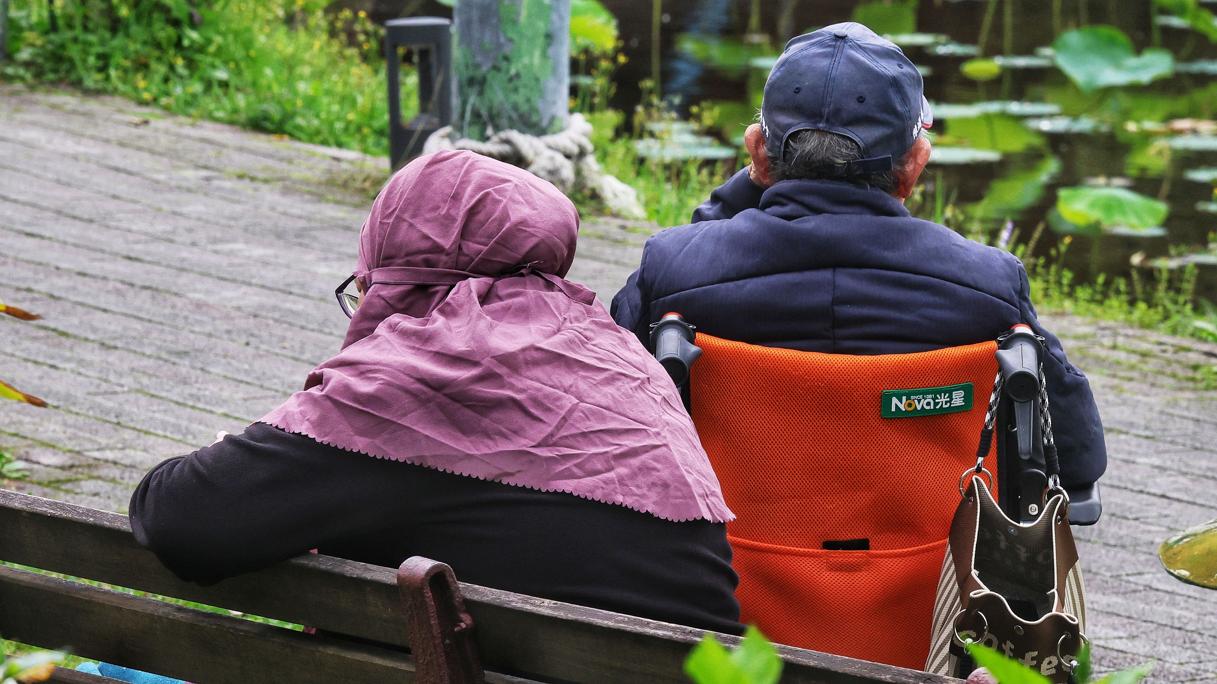 解密報告健保專題配圖：外籍看護推輪椅、年長者坐輪椅。（柯承惠攝）