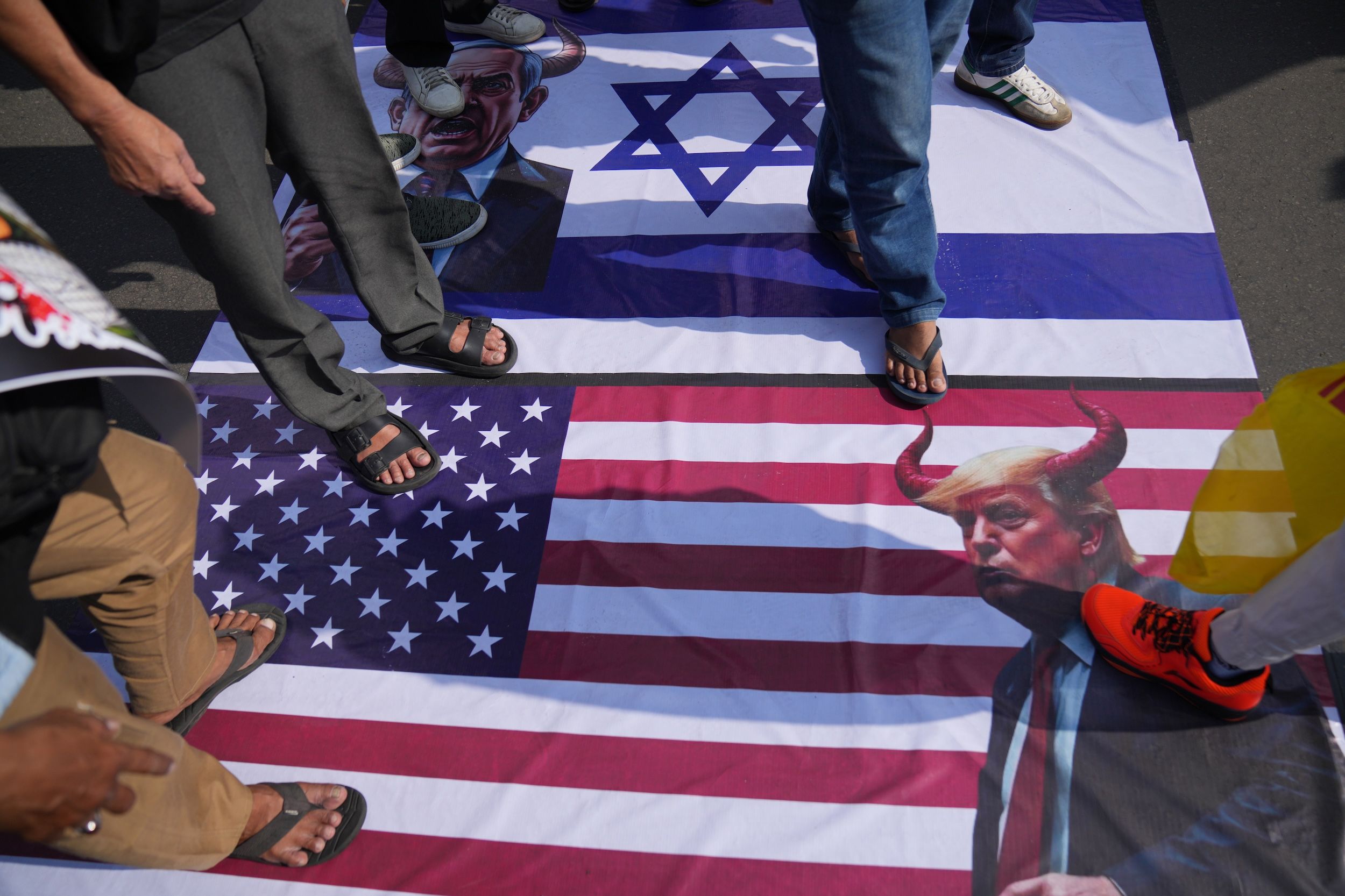 2026年3月13日,印尼雅加達的美國大使館外正在舉行「聖城日」集會,抗議者踩在美國和以色列國旗、還有川普和納坦雅胡的照片上。(美聯社)
