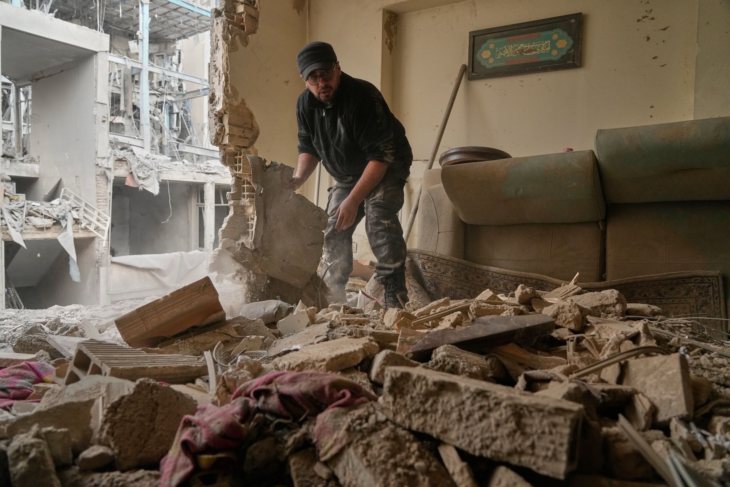 2026年3月15日,美國與以色列的空襲過後,伊朗德黑蘭一名男子正在清理公寓內的瓦礫。(美聯社)