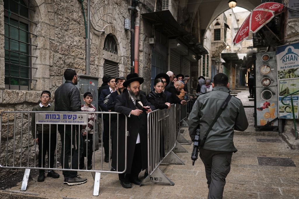 以色列士兵經過一群正統派猶太人群體。（美聯社）