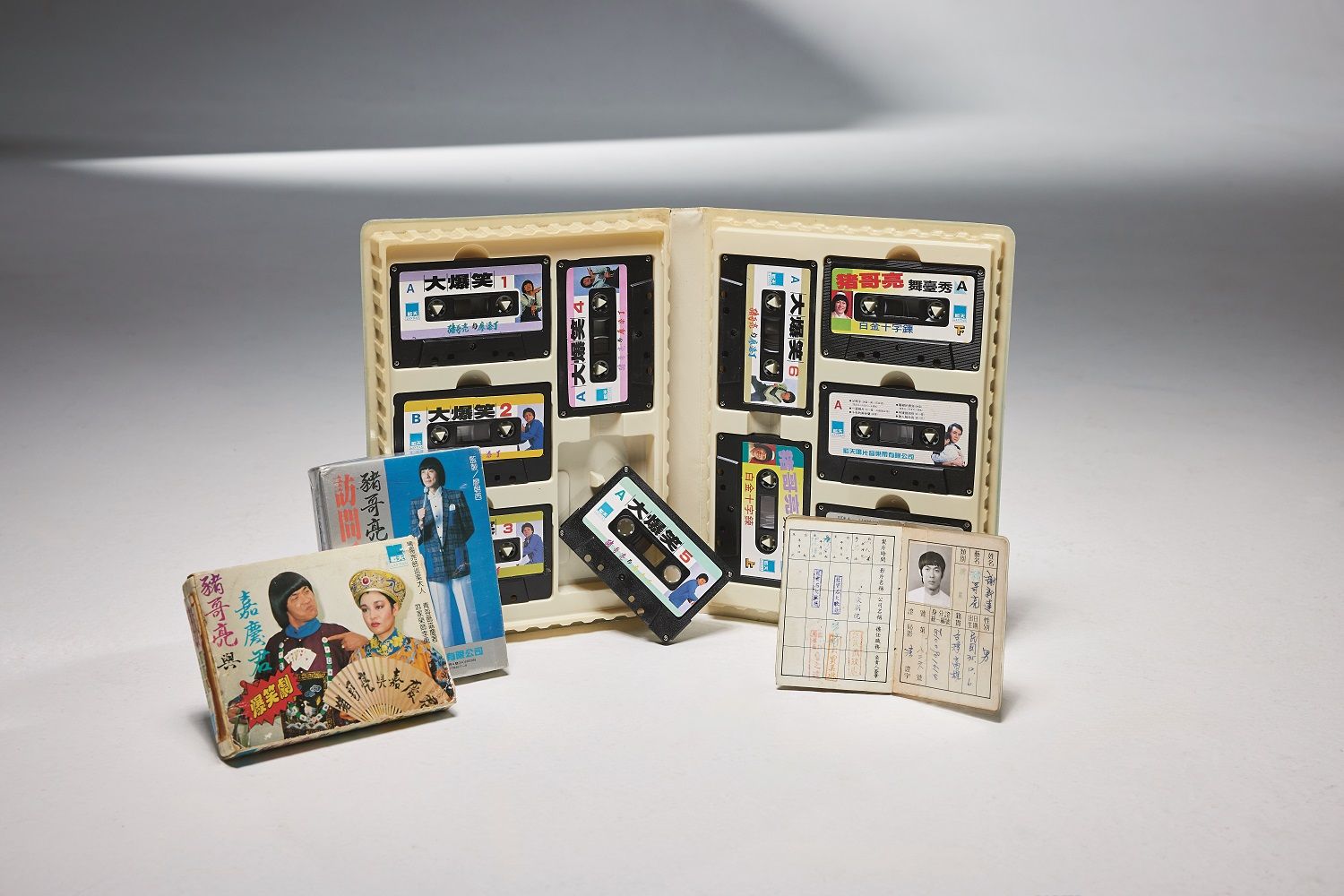 《豬哥亮與嘉慶君》、《豬哥亮與廖添丁》錄音帶，以詼諧口白大受歡迎。右下角，為豬哥亮的演員證，其上姓氏有將「朱」改成「豬」的塗改痕跡。（圖／遠流提供）