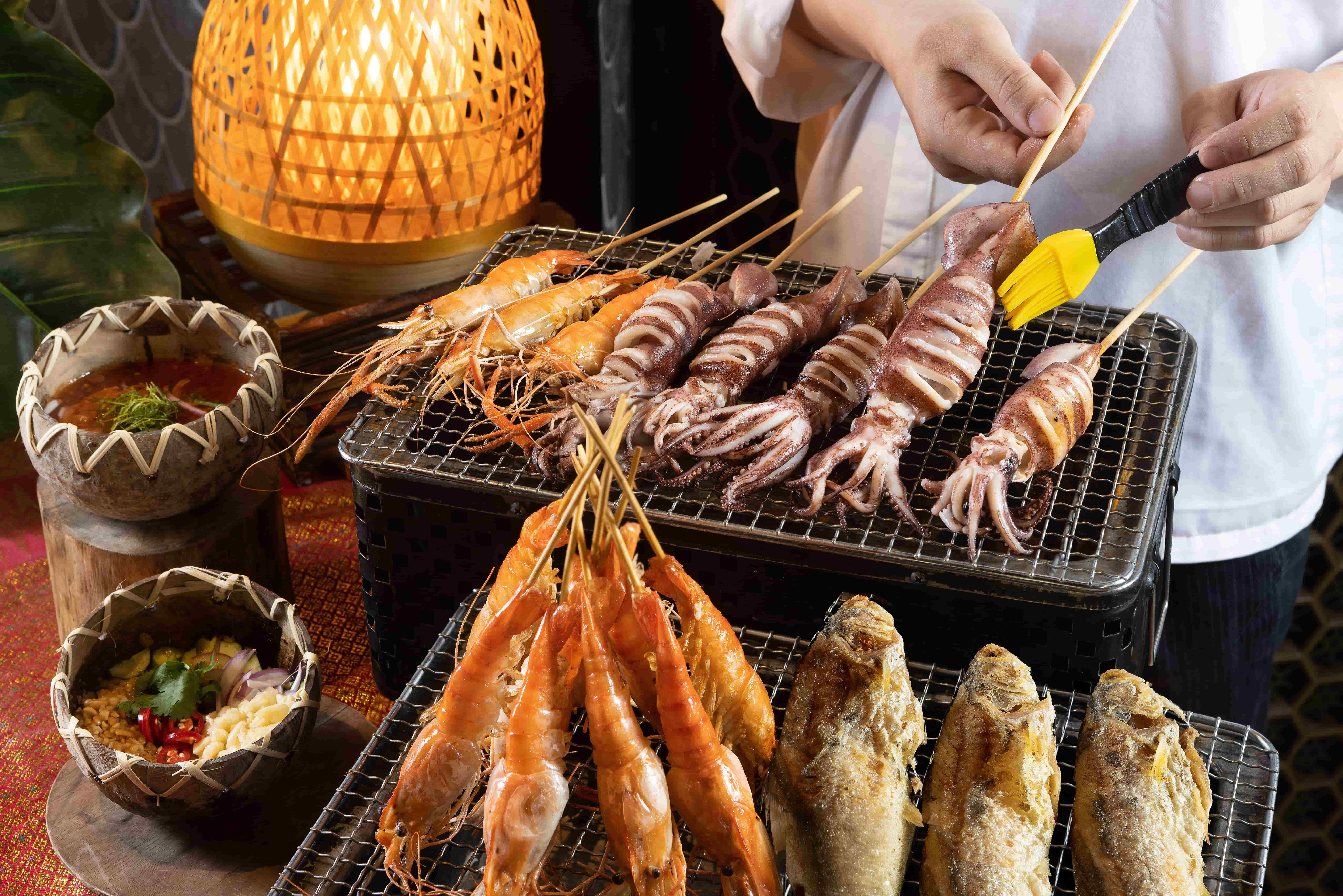 泰市場二周年歡慶活動中，吸睛菜色包含炭香四溢的「現烤海鮮檯」，匯集泰國蝦、魷魚與午仔魚等精選海味，經炭烤釋放細緻焦香，搭配石臼辣醬與花生香蒜汁更加襯托海鮮的鮮甜滋味。（圖/台北晶華提供）