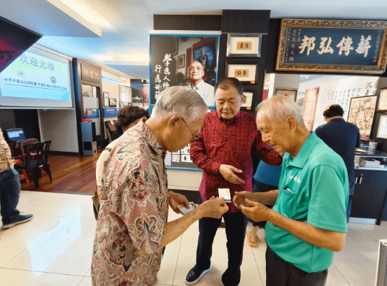 國防部長伍世文上將與沈墨義先生交換名片，中間為拿督丁重誠。(圖/作者提供)