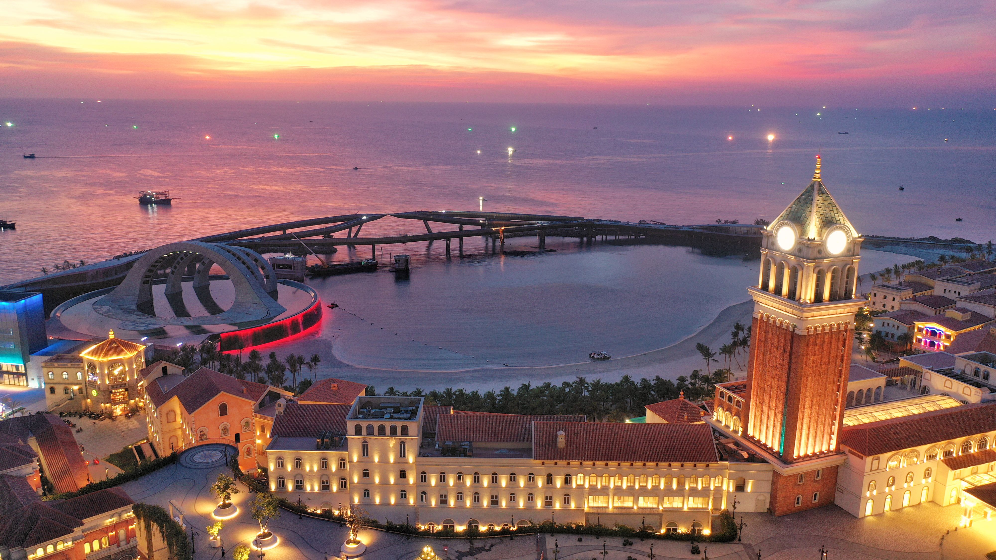 夕陽將Kiss Bridge與海灣染成玫瑰金色，鐘塔與溫暖燈火在夜色降臨前悄然亮起，彷彿整座富國島正為一場浪漫夜晚揭開序幕。（圖/鴻毅旅行社）