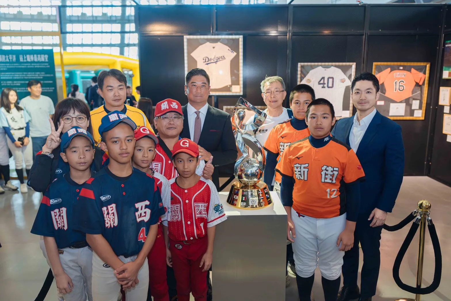 20260517－球星彭政閔（後左1）、中信慈善基金會董事長辜仲諒（後左2）、台北市長蔣萬安（中右1），一同參觀「中信60甲子緣」棒球特展六大展區，與新竹縣關西國中、關西國小、南投縣新街國小師生，於中華隊2024年P12冠軍獎盃前合影。（中信金提供）