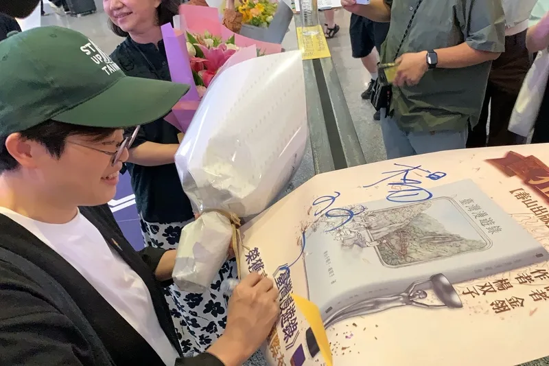 「臺灣漫遊錄」作者楊双子返台（2） 台灣作家楊双子（左）和譯者金翎以長篇小說「臺灣漫遊錄」勇奪2026年國際文學大獎國際布克獎，楊双子26日搭機返台，為接機群眾簽名留念。中央社記者吳睿騏桃園機場攝115年5月26日