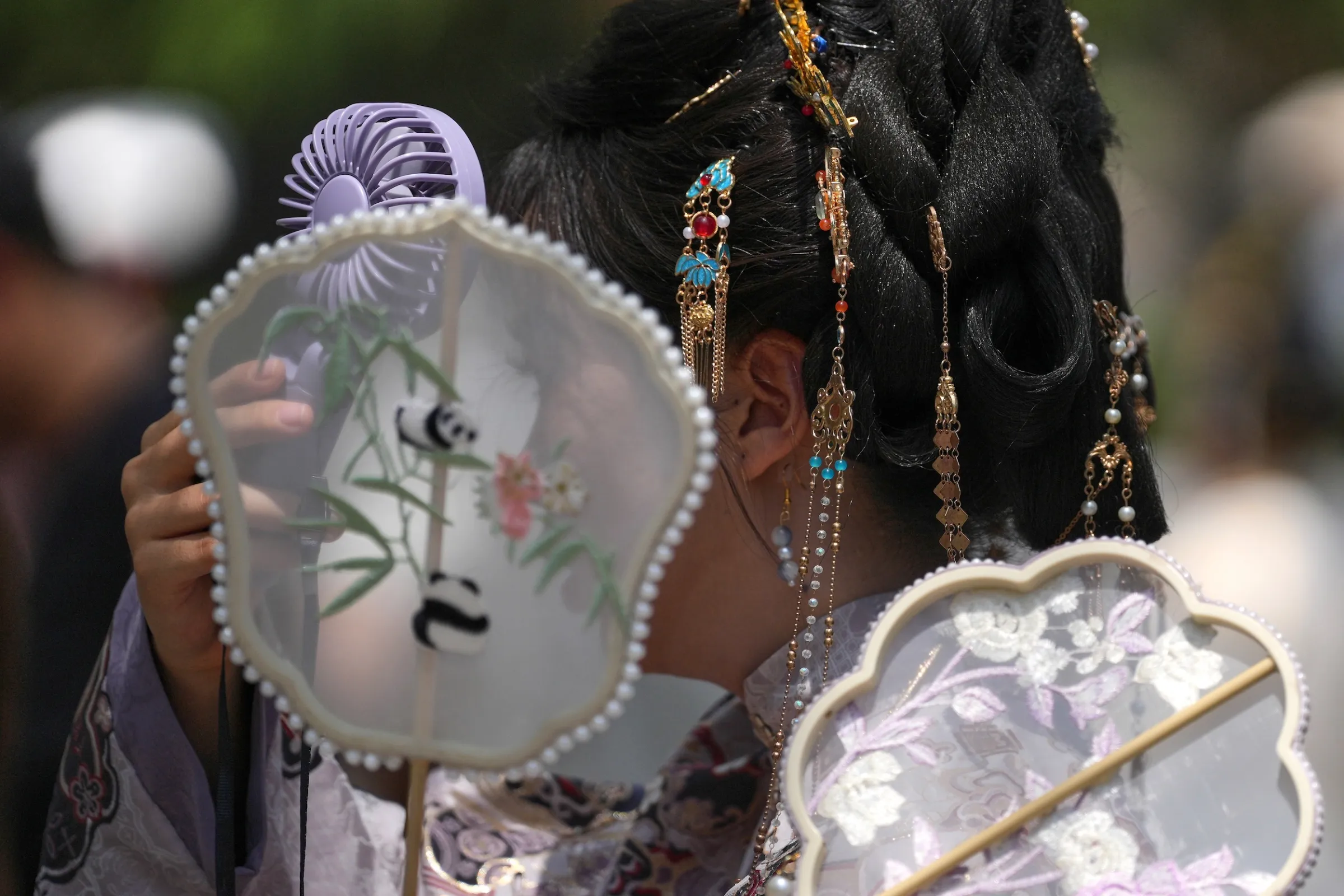 2026年5月31日，中國北京，一名身著傳統漢服的女子在炎熱夏日使用便攜式電扇降溫。（美聯社）