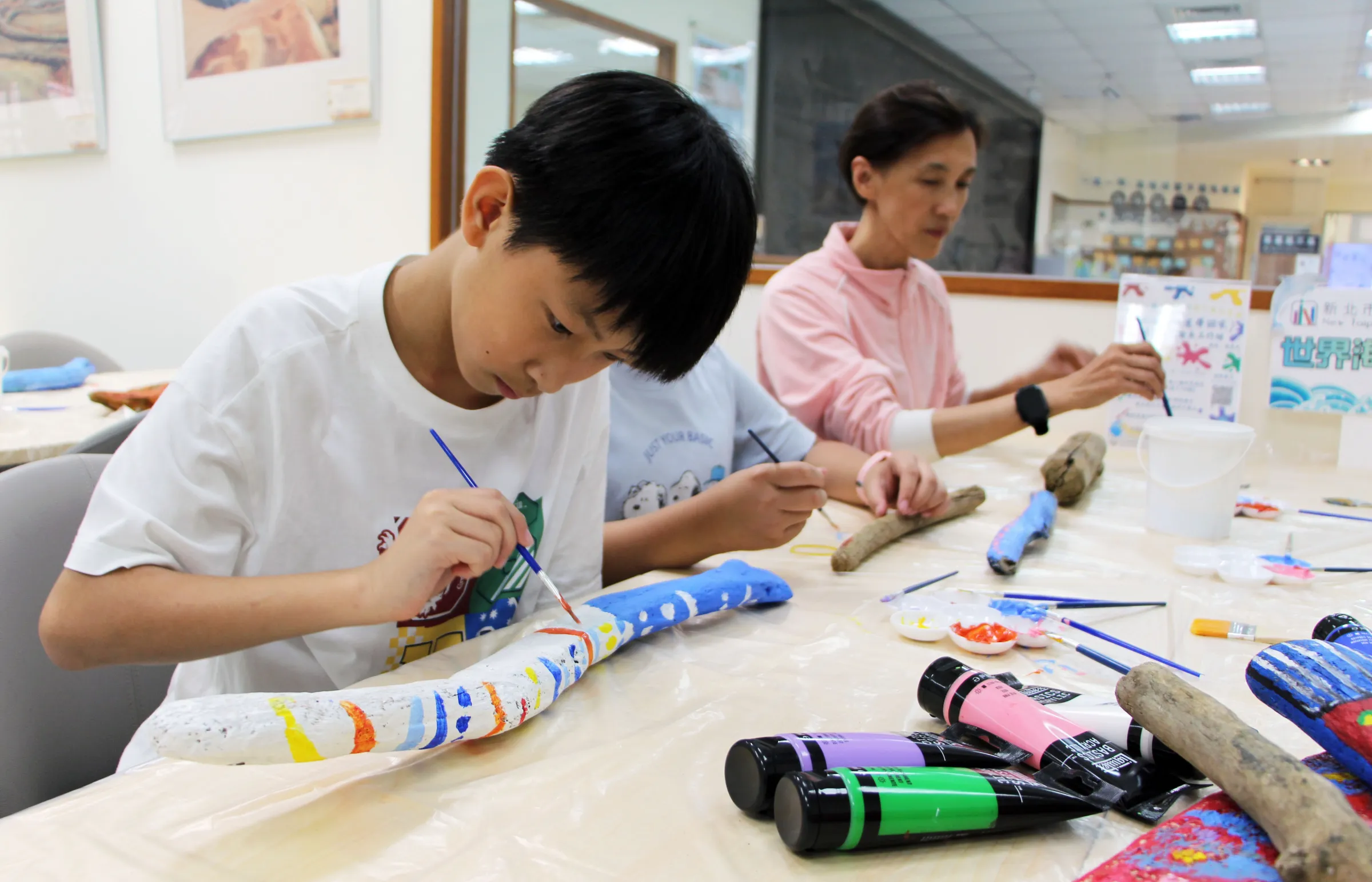 藝術家帶領親子運用北海岸漂流木進行彩繪創作，讓漂流木從海灘上的垃圾，變成充滿創意的藝術品。（圖/新北市立圖書館）