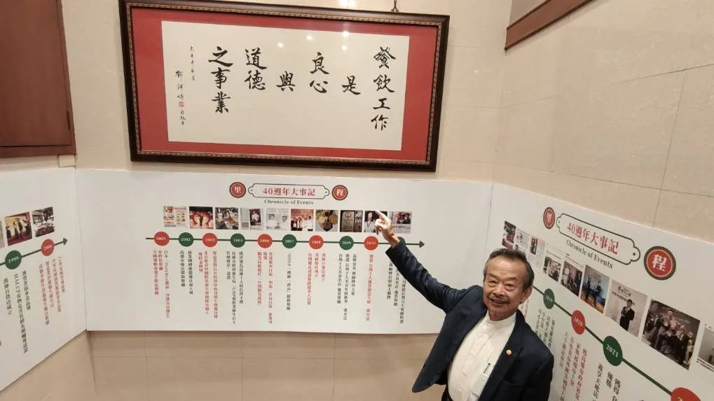 鄧文裕指著「餐飲工作是良心與道德之事業。」的匾額，作為傳家核心價值精神。（圖:徐炳文攝）