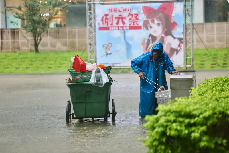 北市午後強降雨　松菸積水（3） 台北市區18日午後降下豪雨，據市府統計，截至下午4時止共接獲41件災情通報，其中37件為積淹水。圖為台北松山文創園區清潔人員冒雨踩過積水，清理園區垃圾箱。中央社記者王飛華攝115年6月18日