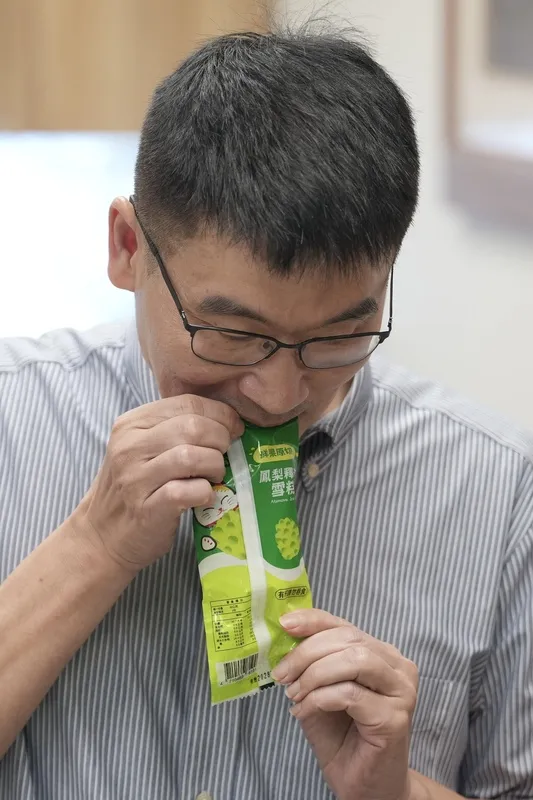 梁文傑品嚐鳳梨釋迦冰棒 台東縣長饒慶鈴日前提及鳳梨釋迦外銷高度依賴中國市場，引發各界對其產銷模式的討論。民進黨立委陳瑩22日舉行記者會，邀請陸委會副主委梁文傑（圖）現場品嚐台東特產的鳳梨釋迦冰棒。中央社記者徐肇昌攝115年6月22日