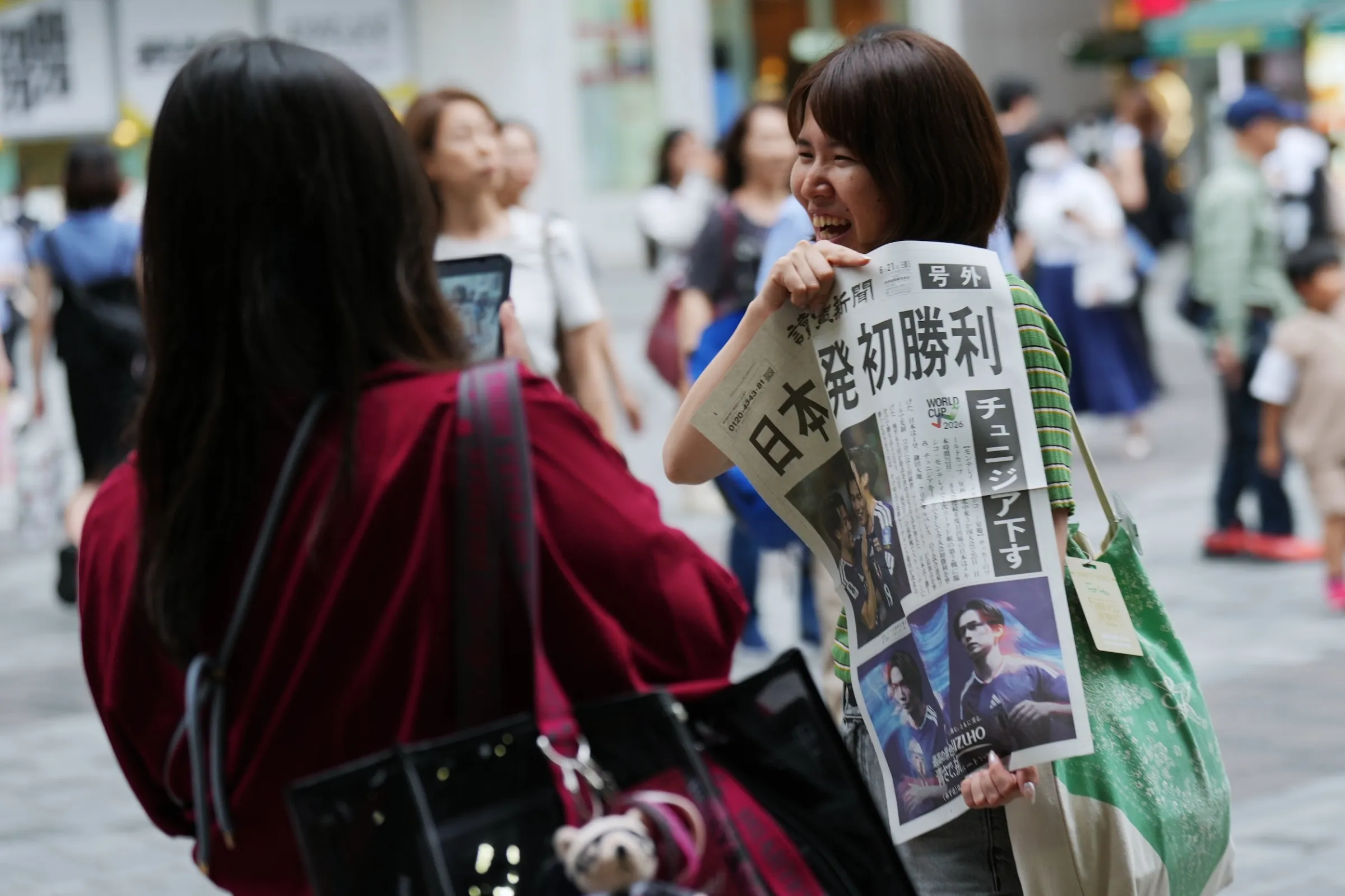 2026年6月21日，在日本隊擊敗突尼西亞後，東京街頭馬上免費發放快報給民眾閱讀。（美聯社）