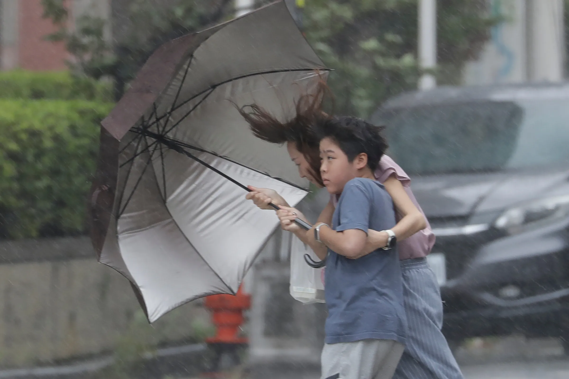 2026年7月11日，巴威颱風來襲，台中民眾艱難撐傘前行。（美聯社）