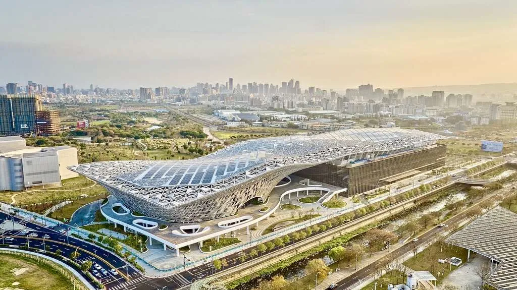 台中國際會展中心位於水湳經貿園區，流線型屋頂與大面積會展建築座落於水湳經貿園區，周邊可見公園綠地與道路。（圖／取自台中官方旅遊網）