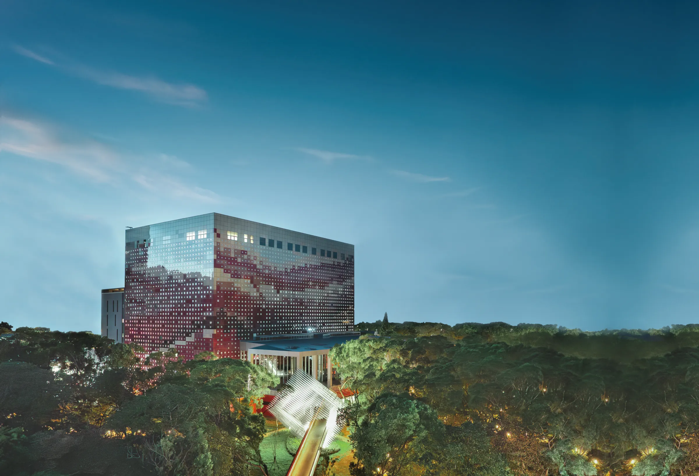 國家檔案館建築外觀，紅色漸層立面座落於大片綠地之中，館舍周邊保留大片綠地與景觀空間，夜間燈光點亮館舍與周邊景觀。（圖／取自國家發展委員會檔案管理局官方網站）