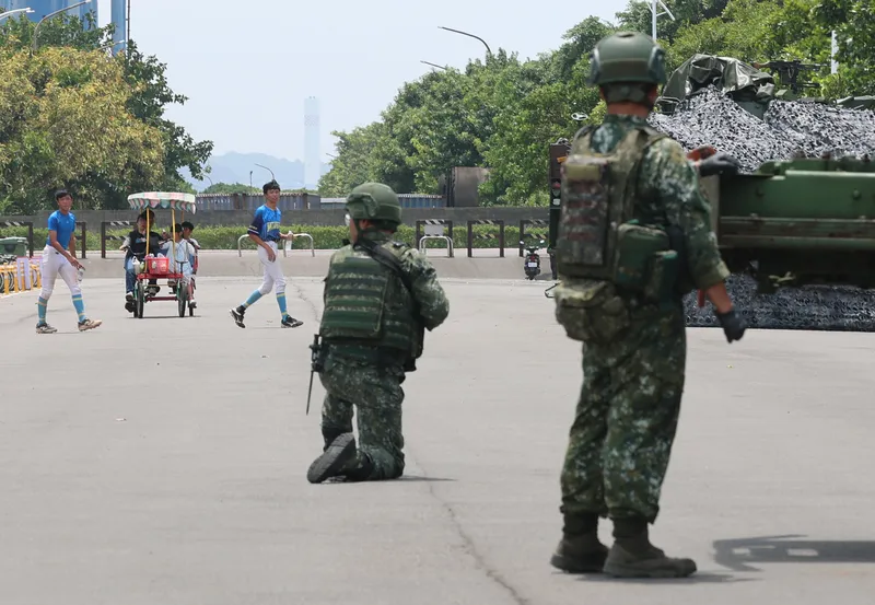 漢光演習八里進行　民眾經過演練場地（2） 國軍漢光42號演習8日在新北八里文化公園執行戰場搶修課目，戰甲車於路上進行吊掛引擎搶修，一旁仍有一般民眾活動，有人騎著協力車經過，也有青少棒球員活動。中央社記者趙世勳攝115年8月8日