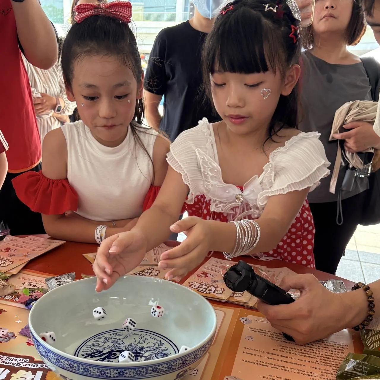 小朋友專注將骰子投入瓷碗，近距離感受金門中秋博餅的緊張與驚喜。（圖／金門縣政府提供）