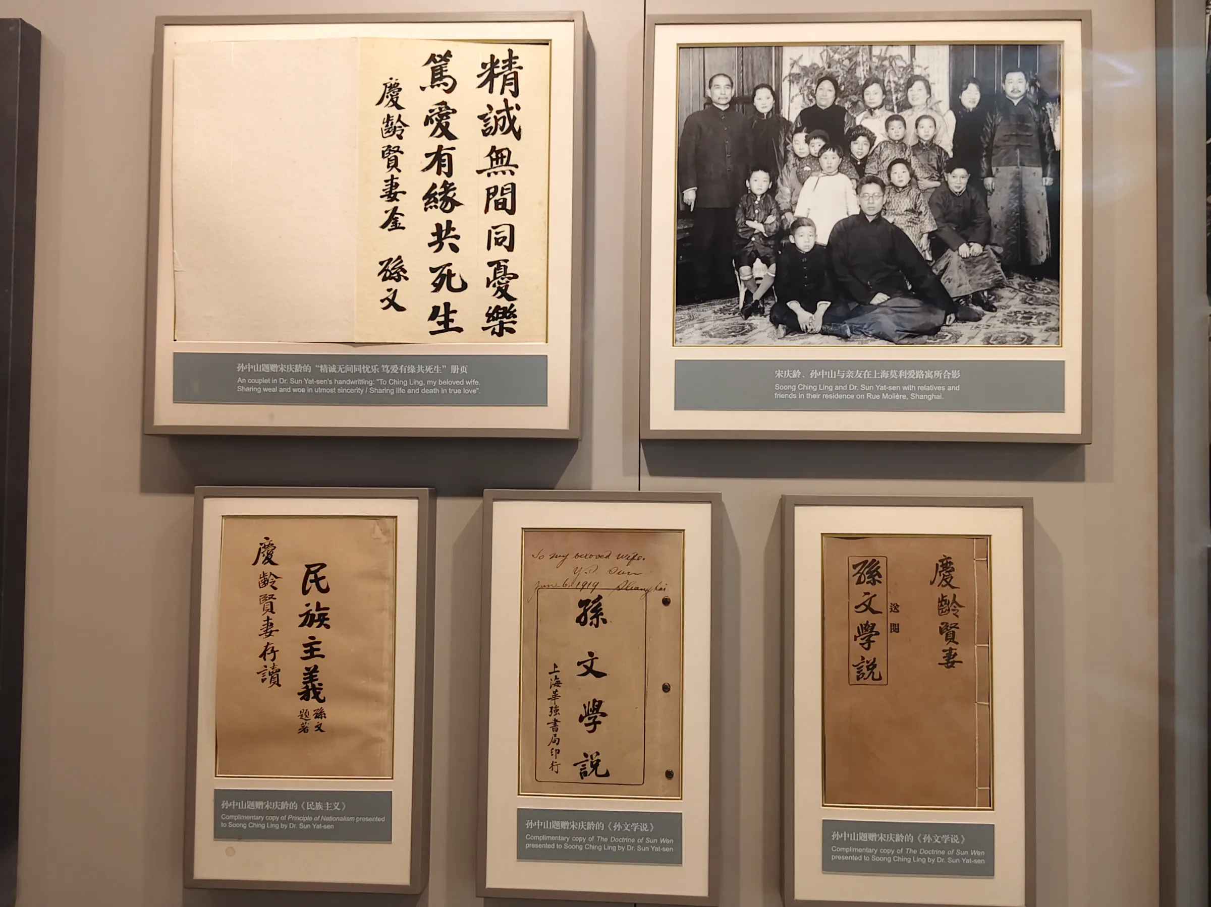故居中展示孫中山給宋慶齡的文稿。右上角照片為孫中山和宋慶齡(後排左一左二)與親友在上海寓所合影。（作者攝）