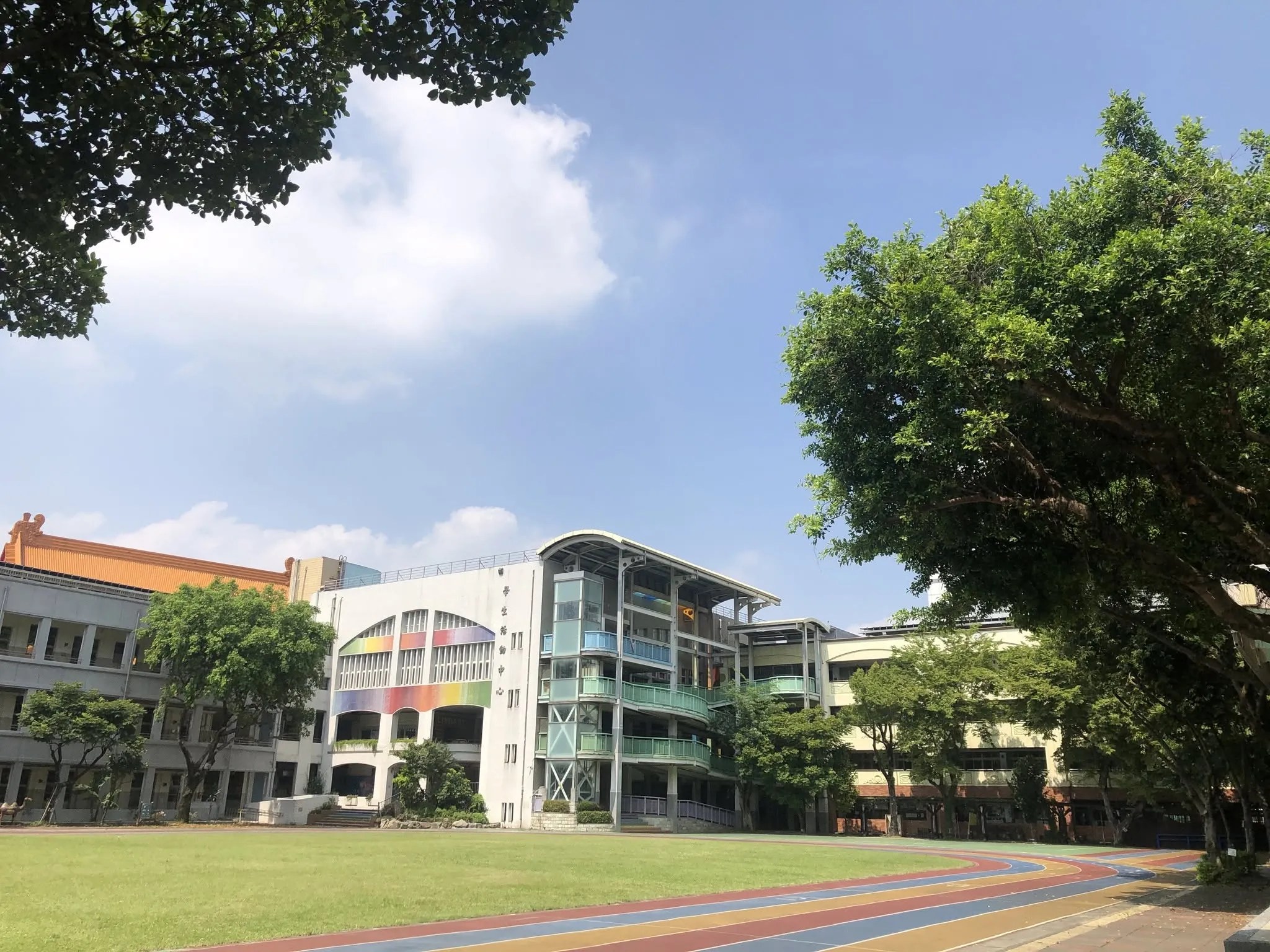 北市中正區東門國小校園操場與校舍，彩色跑道、綠意盎然草坪與後方造型獨特之現代化教學大樓，成為台北明星小學第九名。（圖／取自FB@臺北市立東門國民小學）