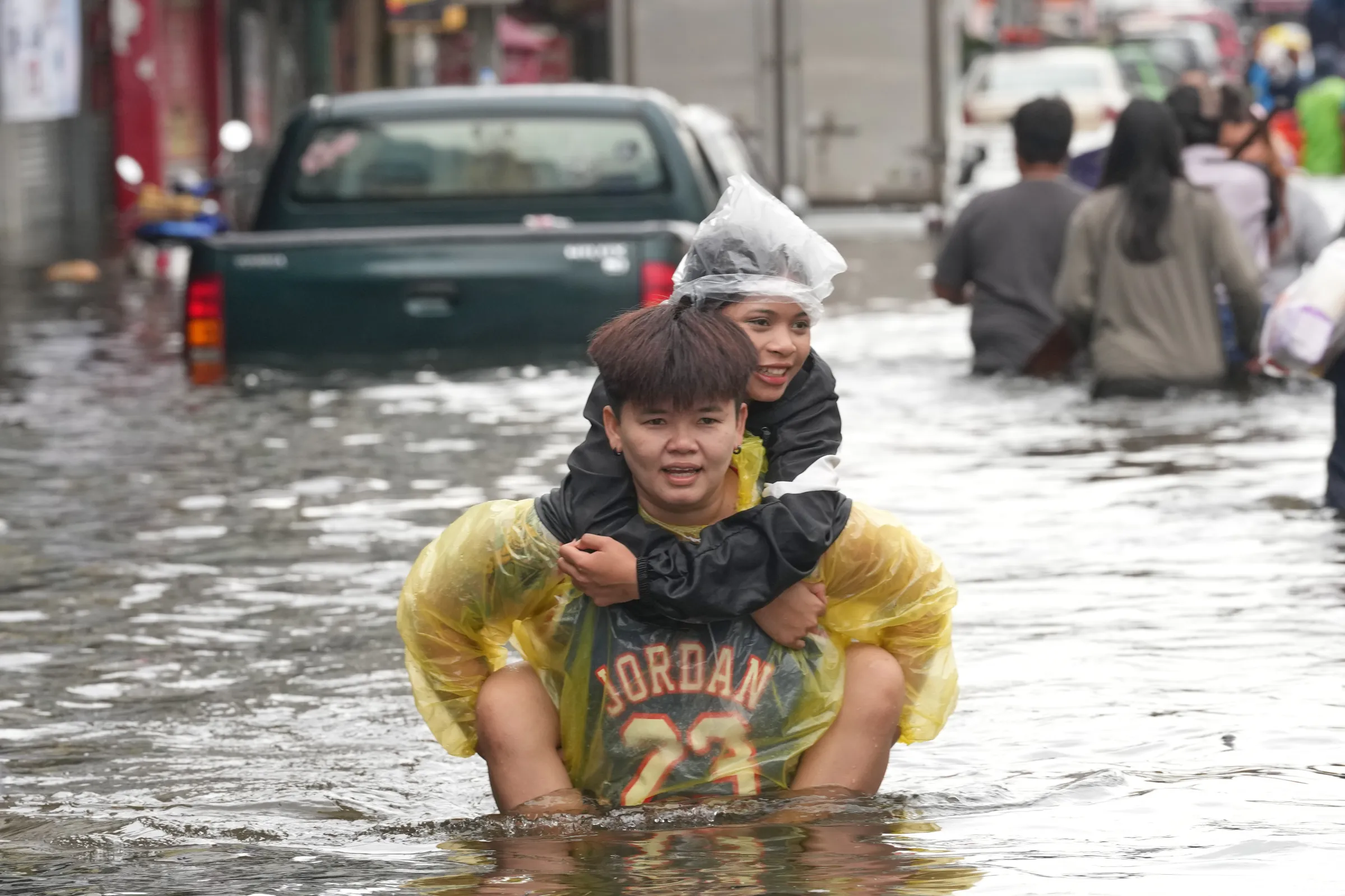 A man carries a woman on his back as they wade through a flooded street in Bangkok, Thailand, Sept. 28, 2026