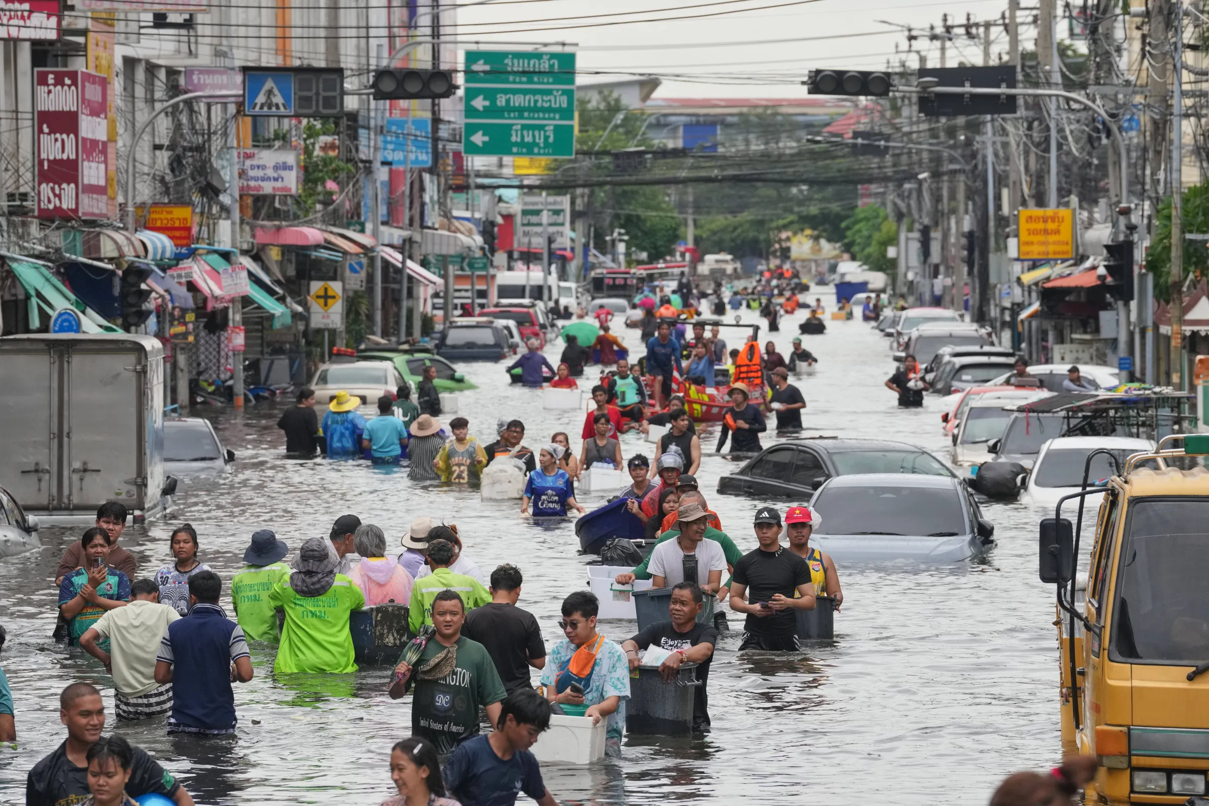 Residents wade through a flooded Bangkok street lined with stalled vehicles after heavy rain, Sept. 28, 2026