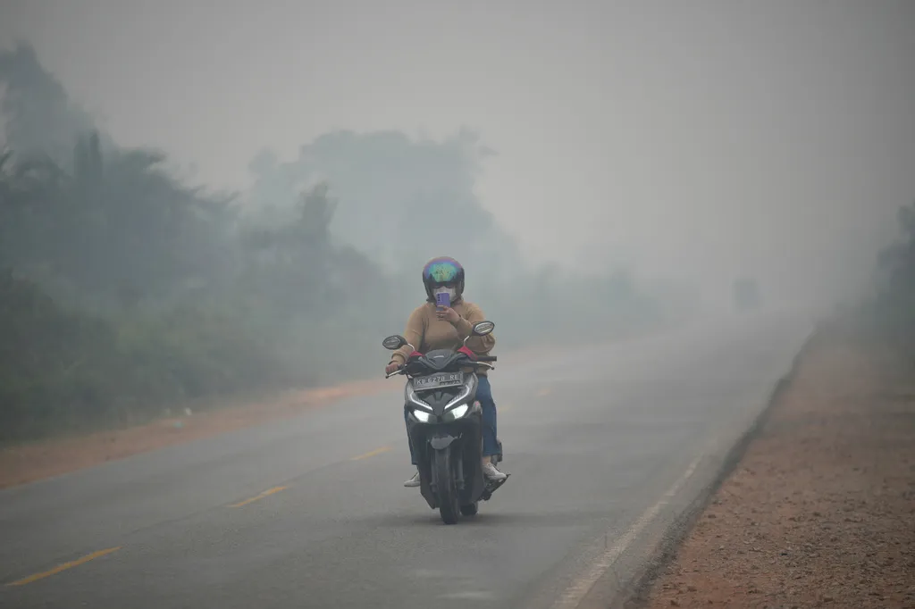 一名印尼機車騎士在空汙天氣下趕路。（美聯社）