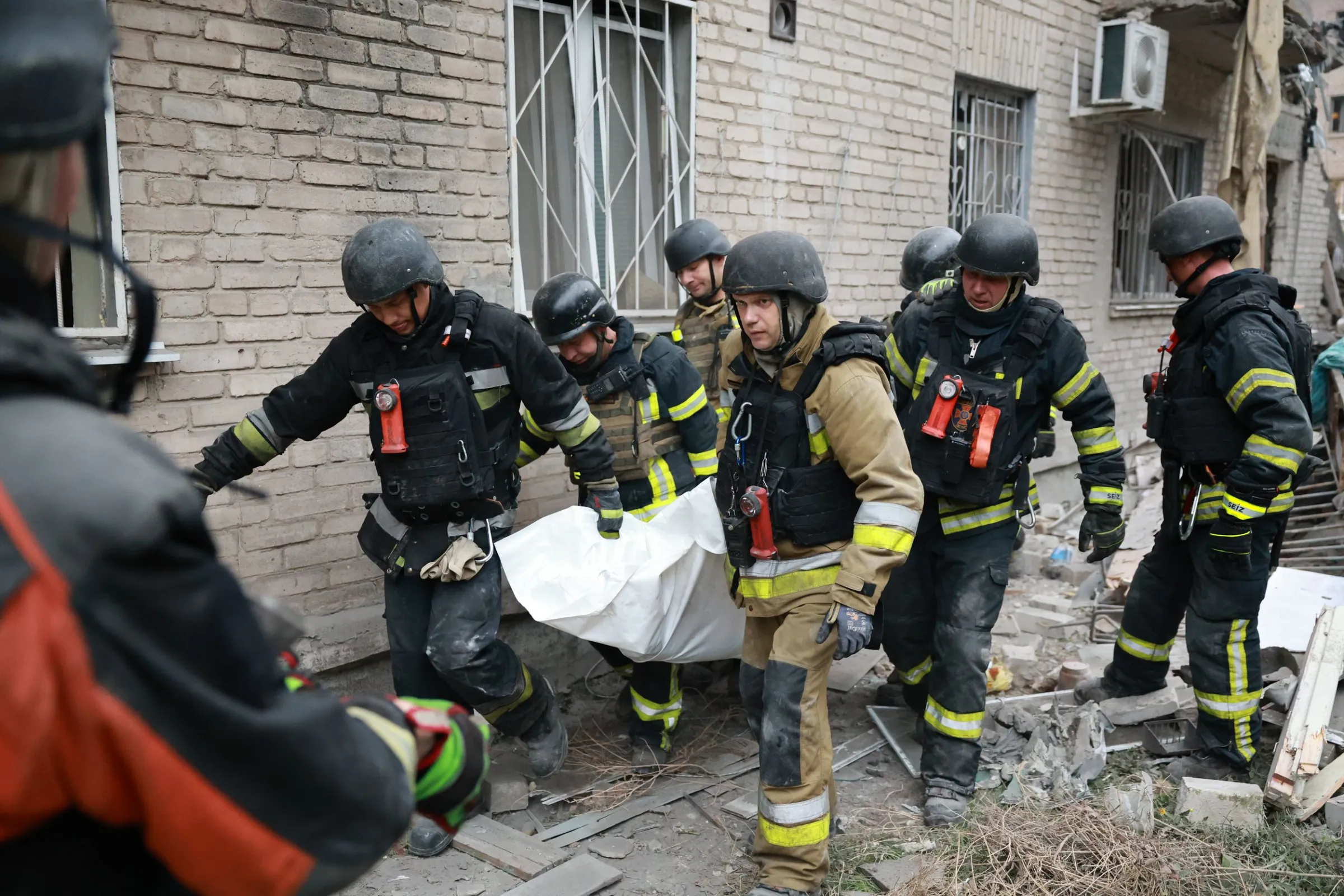 2026年10月10日，烏克蘭札波羅熱，救援人員從遭俄軍空襲摧毀的住宅大樓瓦礫中挖出一具遺體後抬走。（美聯社）