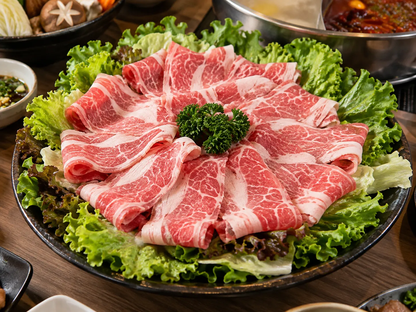 不少火鍋店習慣在生肉盤底下鋪上大片生菜，除了美化擺盤，也讓肉品看起來更有賣相，但這片葉子能不能吃，意外成為網友熱議話題。（示意圖／ChatGPT）