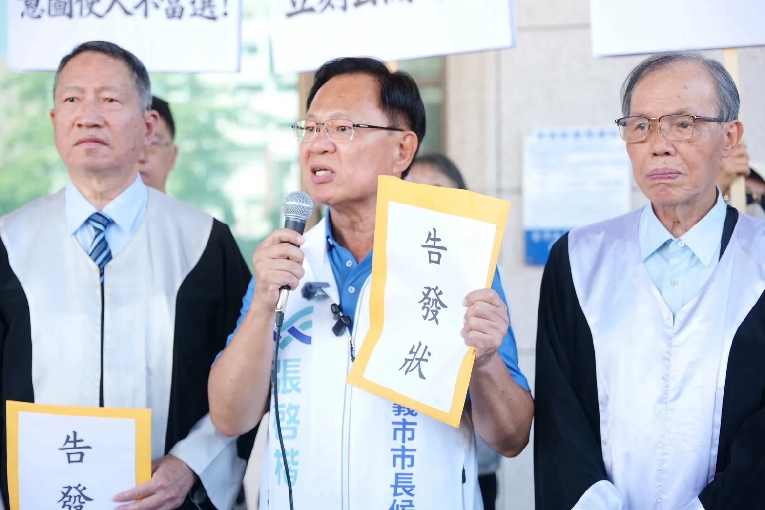 張啓楷手持封面標示「告發狀」的文件，在律師陪同下向媒體說明提告主張。（圖/張啓楷競辦提供）